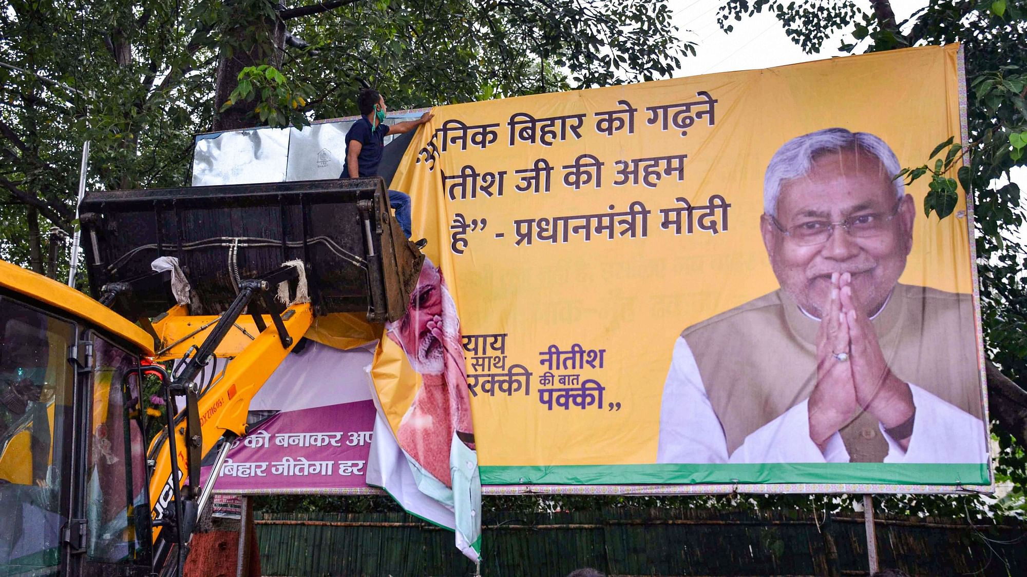 Workers remove a hoarding of Bihar CM Nitish Kumar as per model code of conduct following announcement of Bihar Assembly Election dates, in Patna, Friday, 25 September 2020.