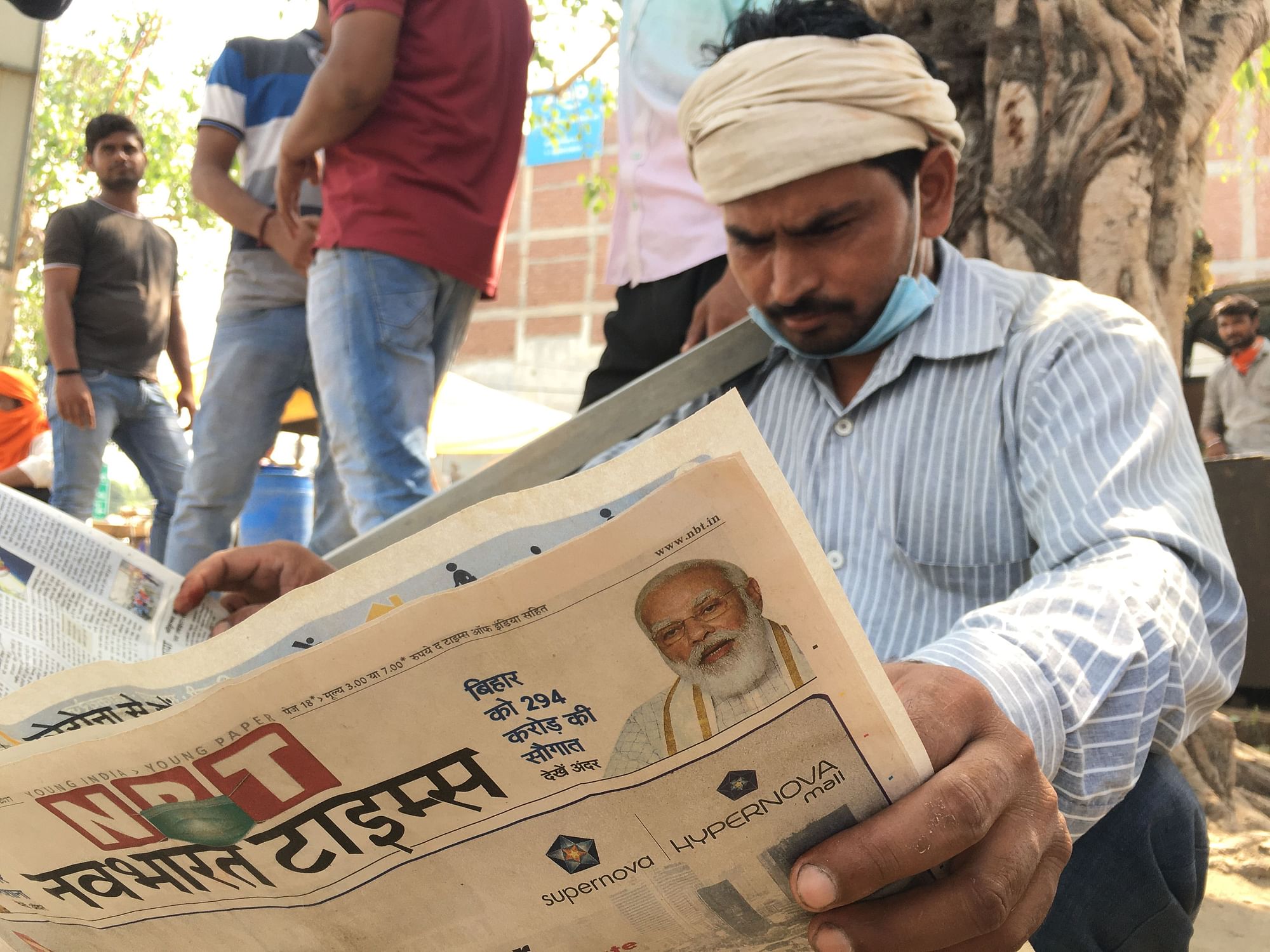 A daily wage earner reading newspaper at Noida Labour Chowk.