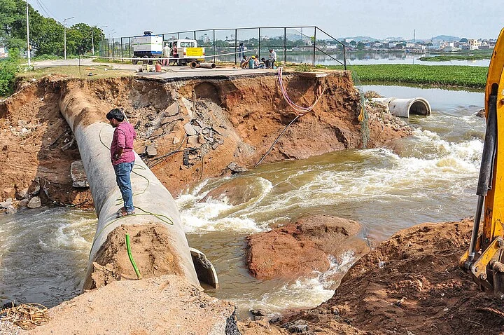 A man looks on at the damaged portion of the retaining walls of Balapur lake, which collapsed last night following heavy rainfall, in Hyderabad, Sunday, Oct. 18