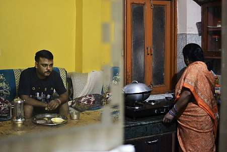 Ajay’s worried reflection while his mother works in the kitchen.