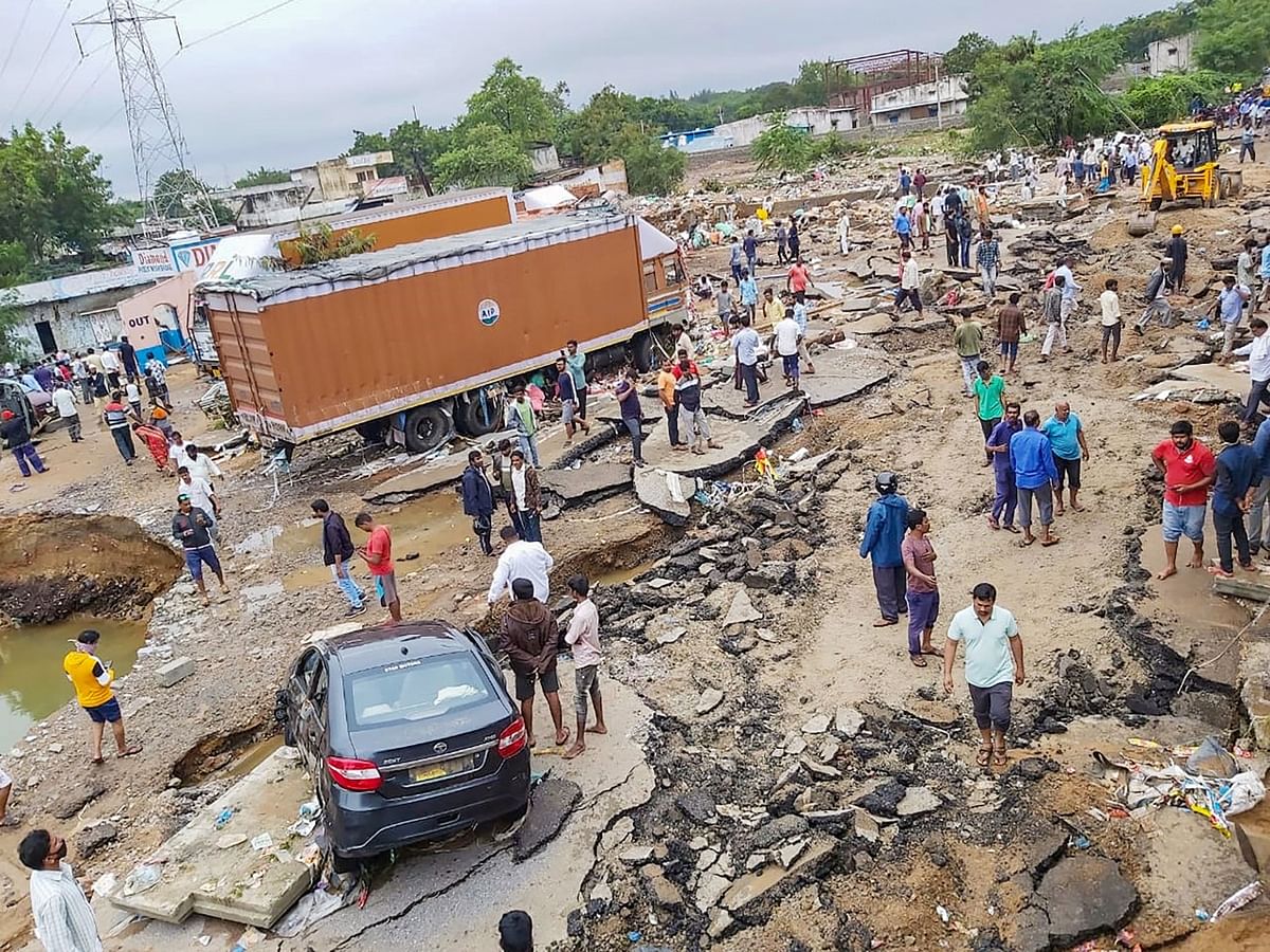 People gather after a road caved-in following incessant rainfall across the state, at Gaganpahad-Shamshabad Road near Hyderabad, Wednesday, Oct. 14, 2020. 