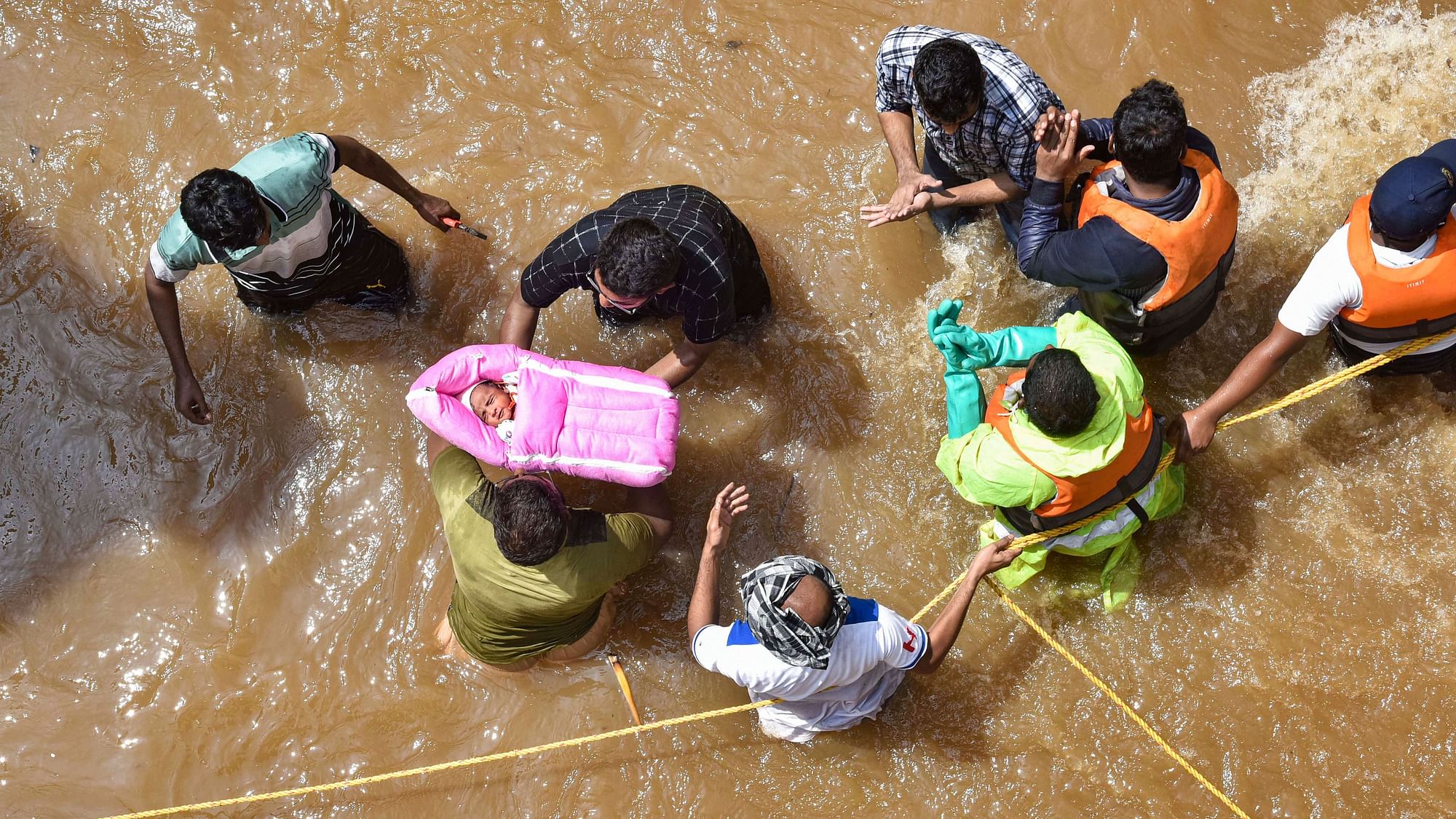 GHMC personnel carry an infant during an operation to move flood-affected people to a safer place, at Hafiz Baba Nagar in Hyderabad, Sunday, 18 October, 2020. 