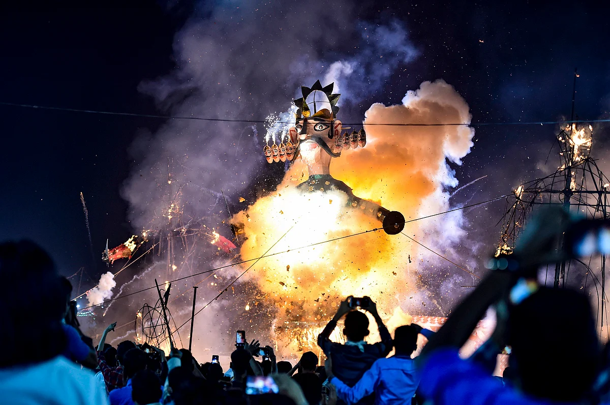 People look on as an effigy of Ravana burns during Dussehra festival, at Karkardooma in New Delhi, Sunday, 25 October.