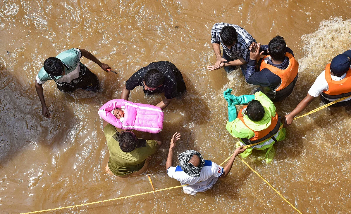 GHMC personnel carry an infant during an operation to move flood-affected people to a safer place, at Hafiz Baba Nagar in Hyderabad on Sunday.
