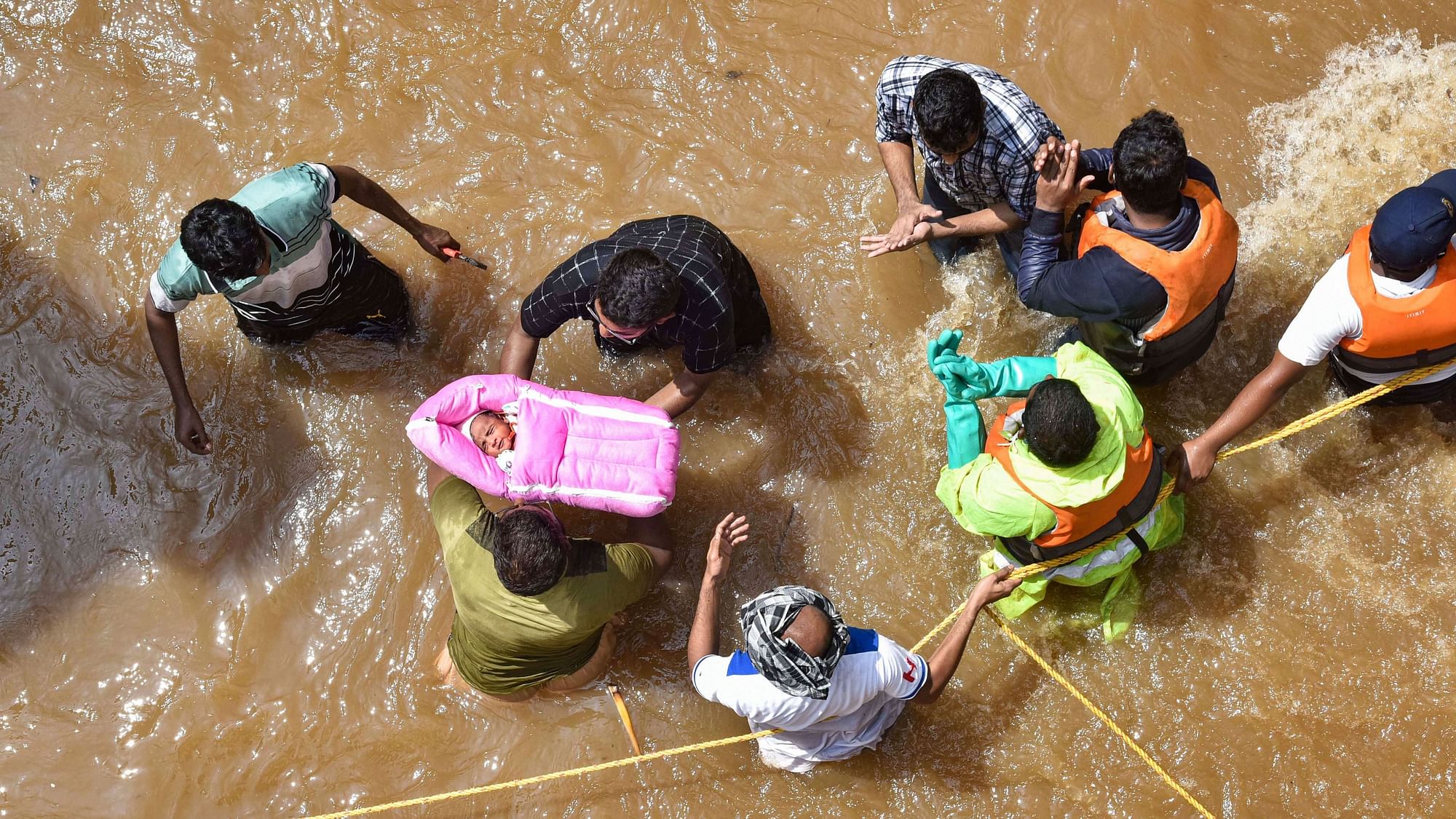 Hyderabad: GHMC personnel carry an infant during an operation to move flood-affected people to a safer place, at Hafiz Baba Nagar in Hyderabad, Sunday, 18 October, 2020.