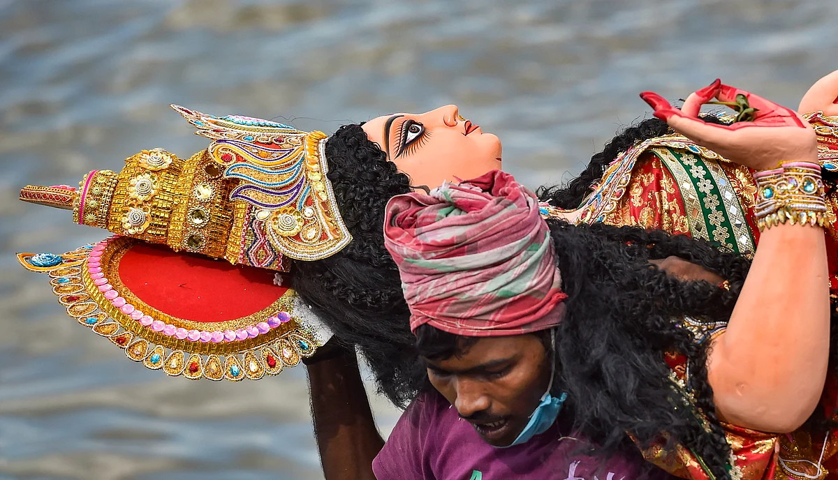A devotee immerses an idol of Goddess Laxmi in Ganga River after offering prayers, in Kolkata.