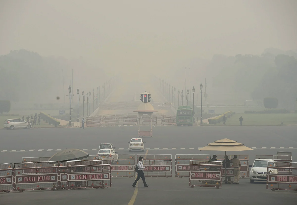 A man crosses a road at Rajpath in the backdrop of an atmosphere shrouded in smog, in New Delhi.