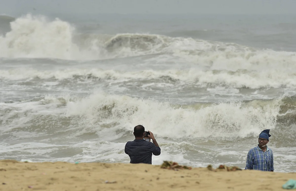 A man clicks photographs as turbulent waves crash the shore before the landfall of Cyclone Nivar, at Marina Beach in Chennai, Tuesday, Nov. 24.