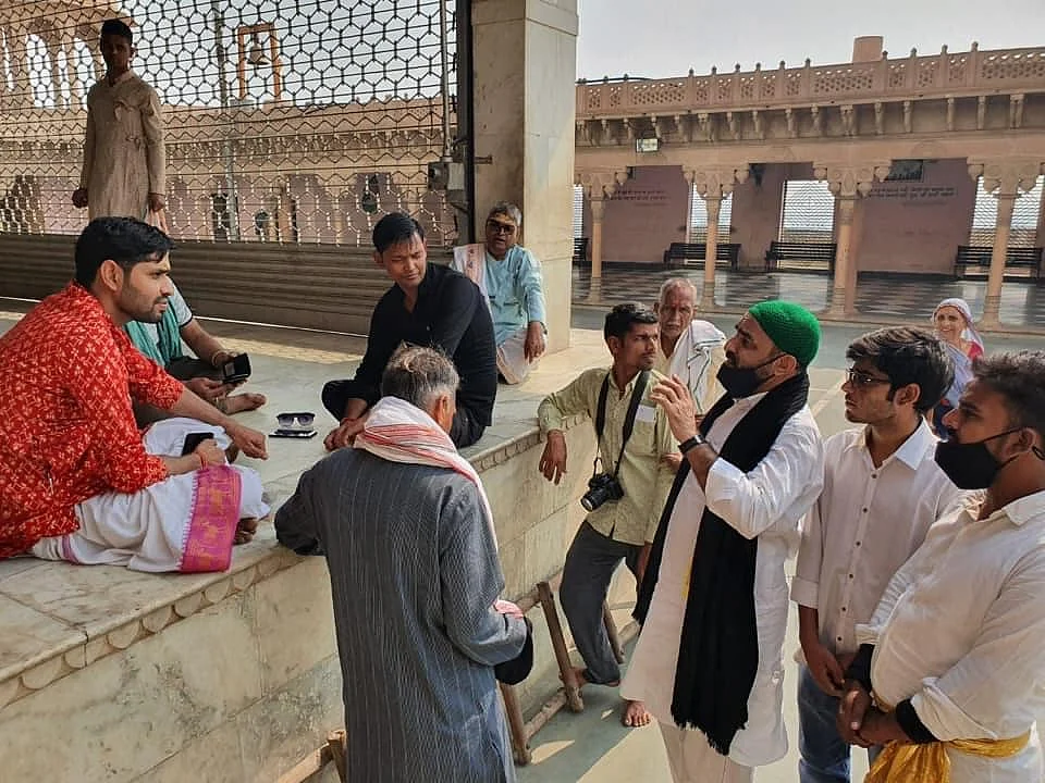This is an image of Faisal Khan (in green cap) along with other members of his organisation and the priests at the temple.
