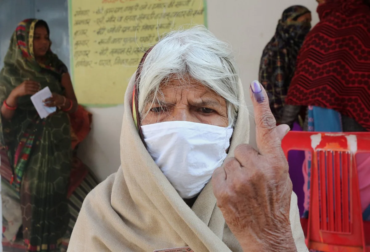 An elderly woman shows her finger marked with indelible ink after casting vote during the Madhya Pradesh Assembly bypolls, amid the ongoing coronavirus pandemic, in Raisen district, Tuesday, 3 November.
