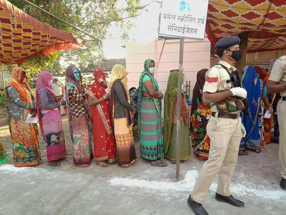 Women stand in a queue to cast their votes during the Madhya Pradesh Assembly bypolls, amid the ongoing coronavirus pandemic, in Indore district, Tuesday, 3 November.