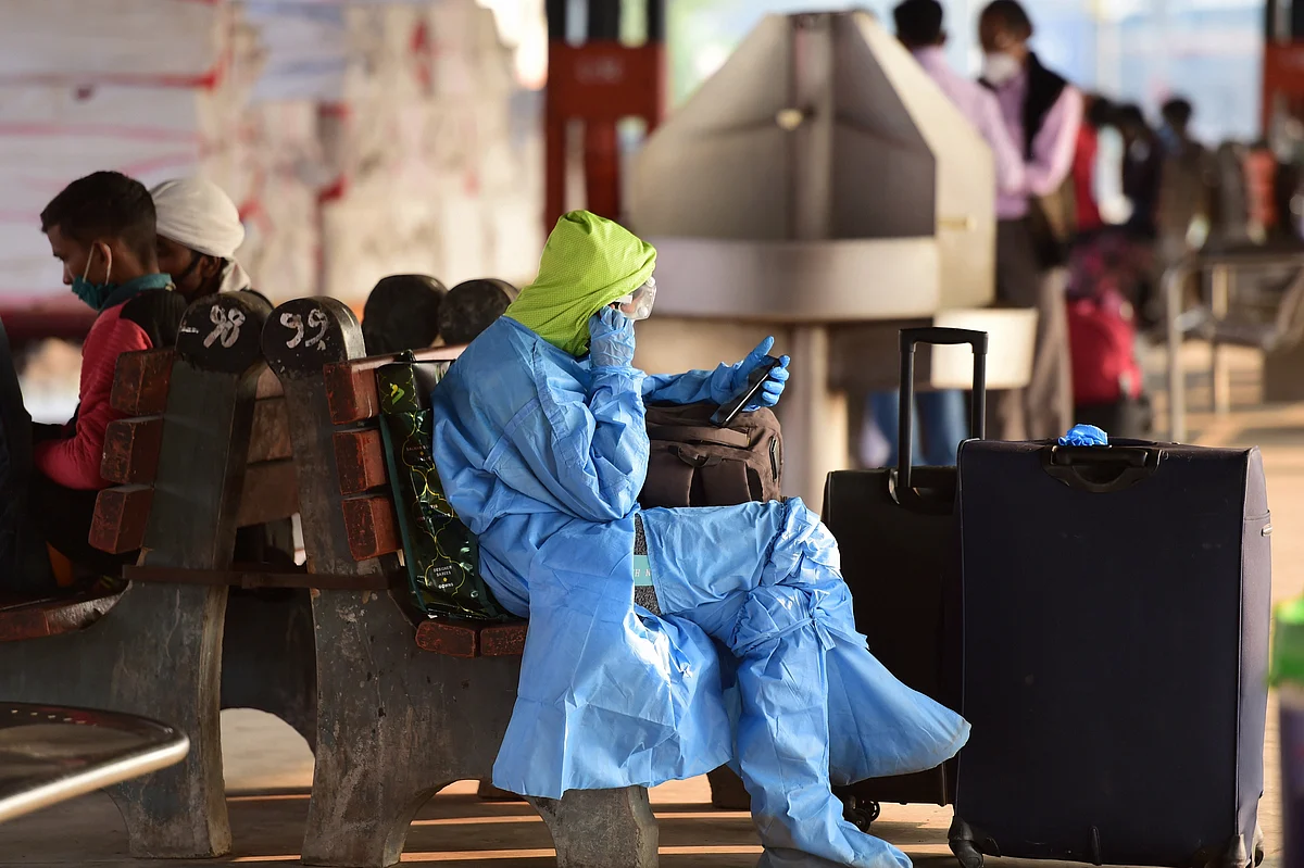 A woman passenger wearing protective suit, waits for train at New Delhi station.