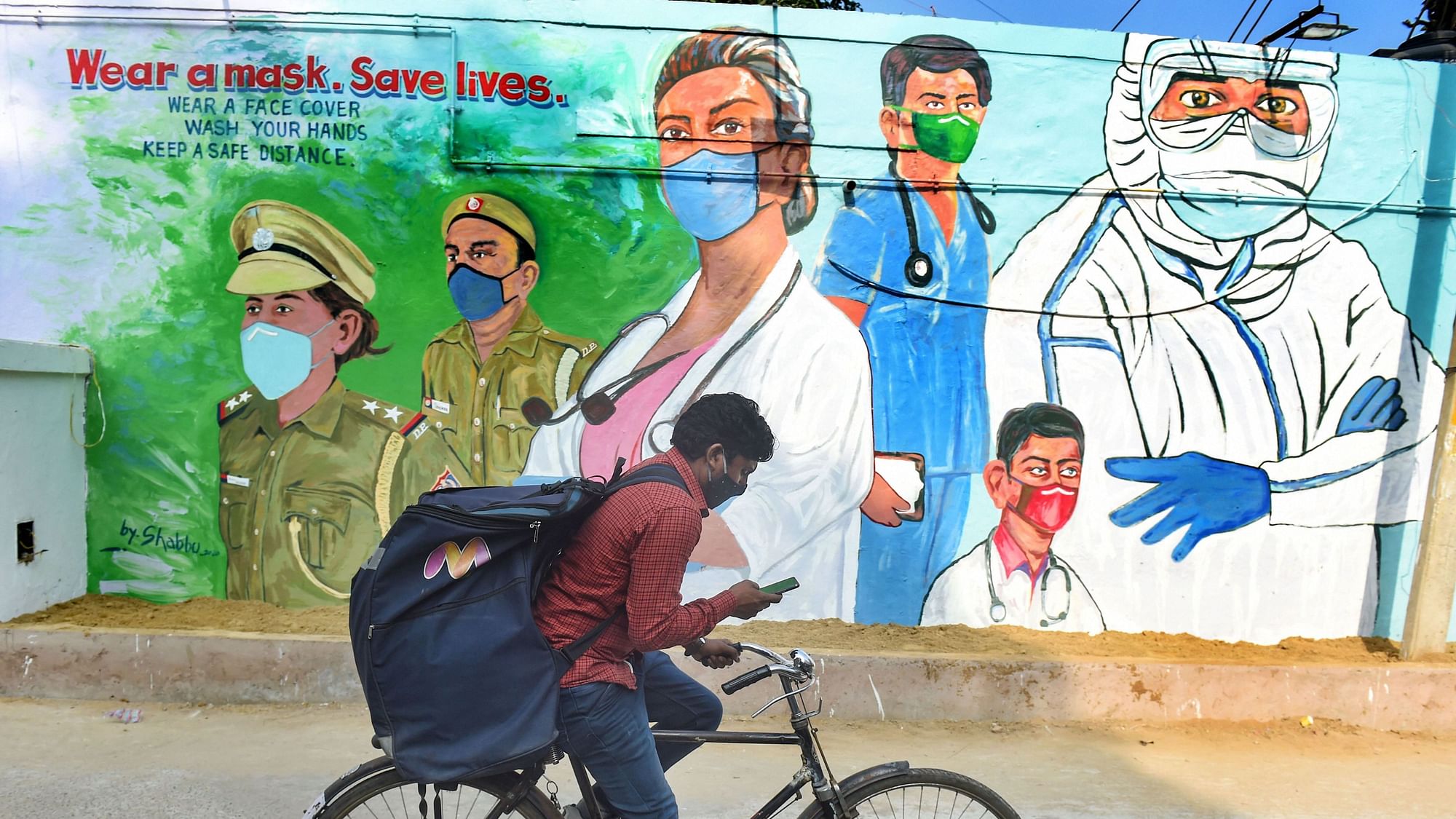 A cyclist rides past a mural, honouring the warriors of COVID-19, in New Delhi, Monday, Dec. 7, 2020.&nbsp;