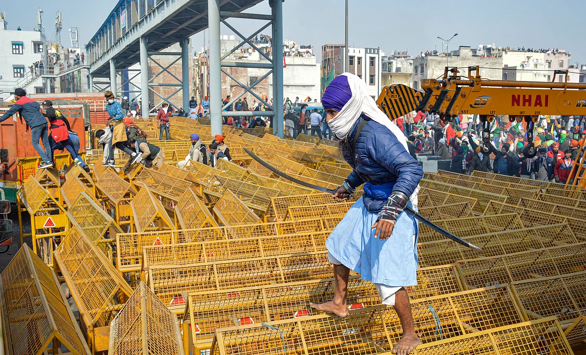 A farmer walks over the police barricades set up on a road at Akshardham to stop farmers during their during the Kisan Gantantra Parade amid the 72nd Republic Day celebrations, in New Delhi, Tuesday, 26 January 2021. 