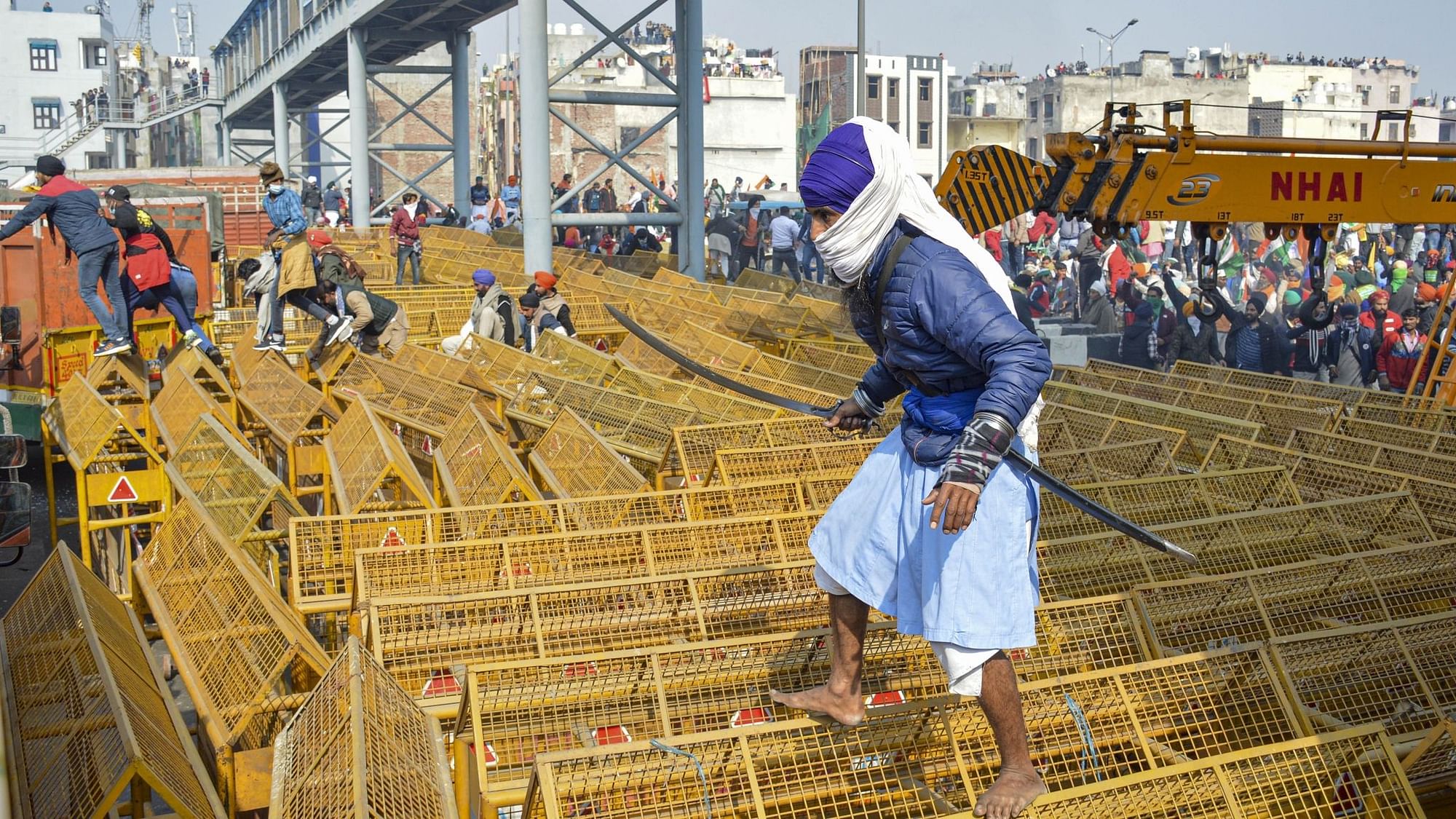A farmer walks over the police barricades set up on a road at Akshardham to stop farmers during their during the Kisan Gantantra Parade amid the 72nd Republic Day celebrations, in New Delhi, Tuesday, 26 January 2021.&nbsp;