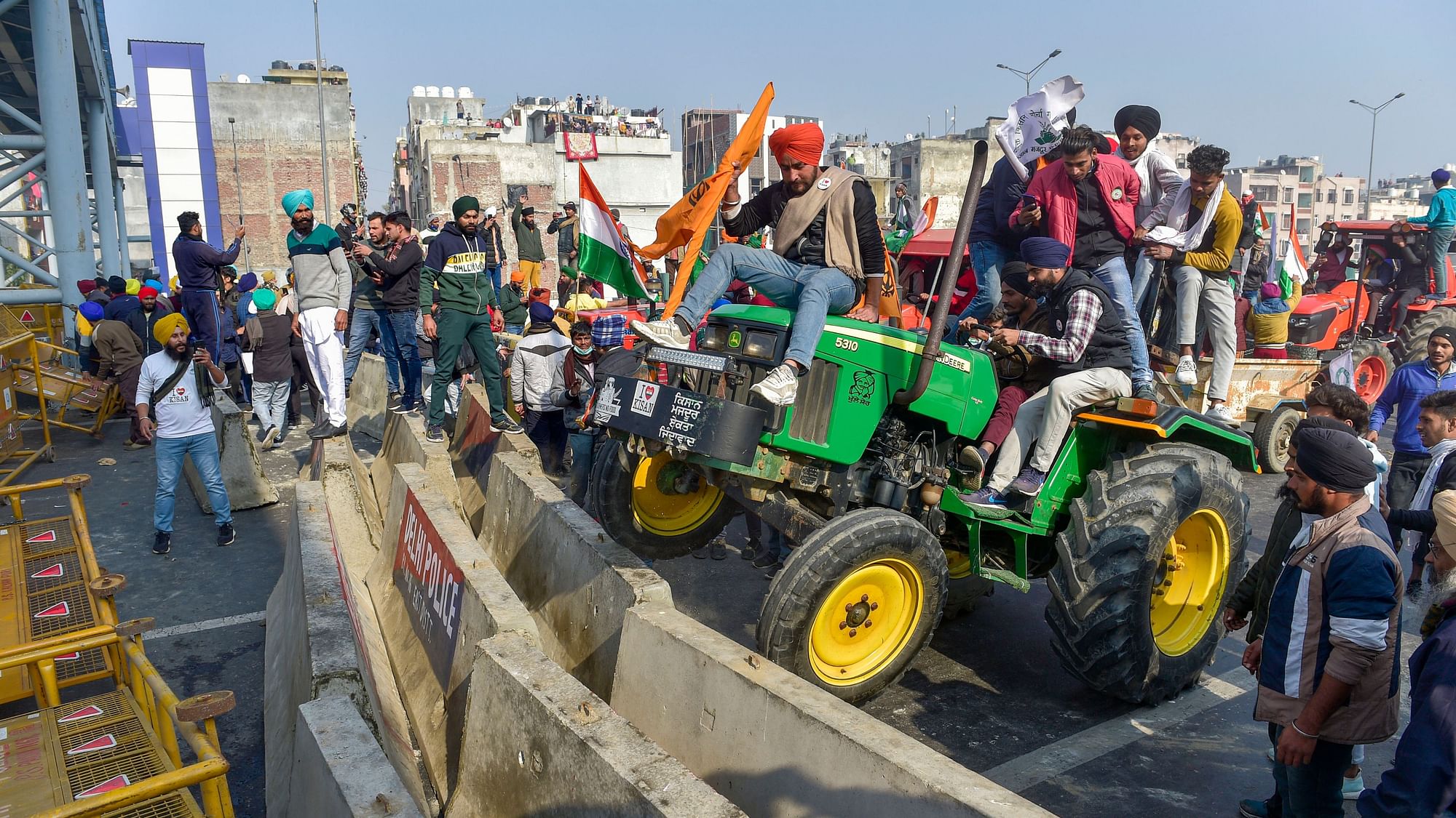 Farmers attempt to break a barricade at Ghazipur border as they participate in Kisan Gantantra Parade in protest against Centres farm reform laws, on the occasion of 72nd Republic Day, in New Delhi, Tuesday, 26 January.