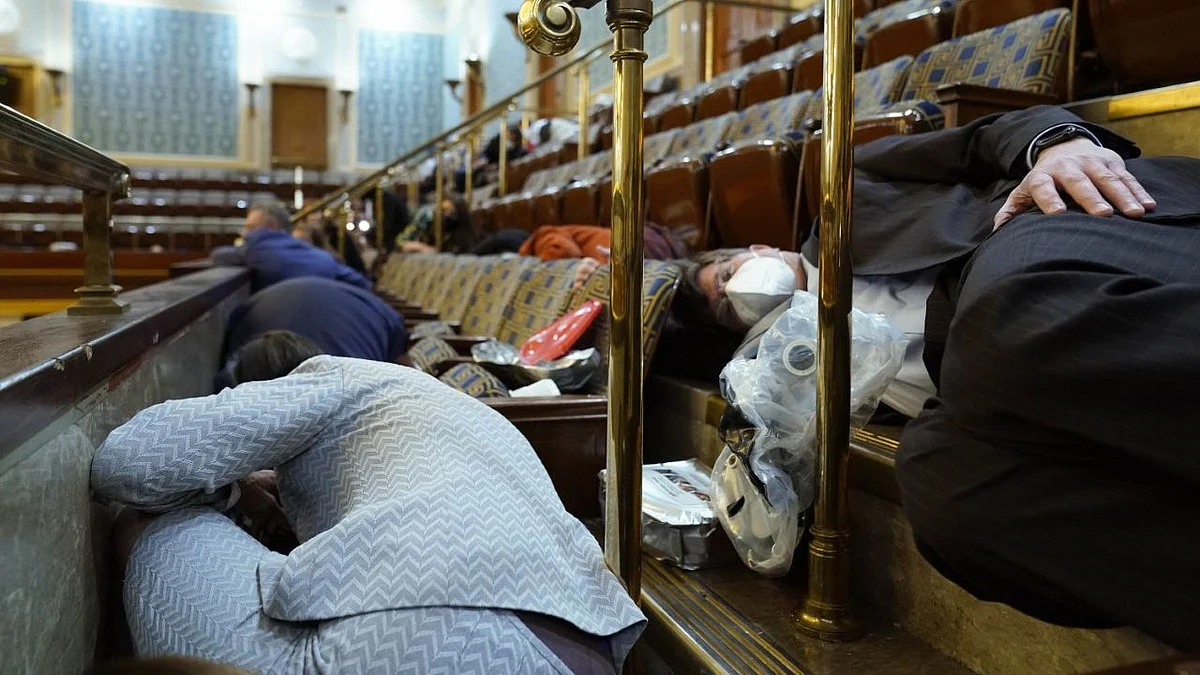 People shelter in the House gallery as protesters try to break into the House Chamber at the US Capitol on Wednesday, 6 January, in Washington.