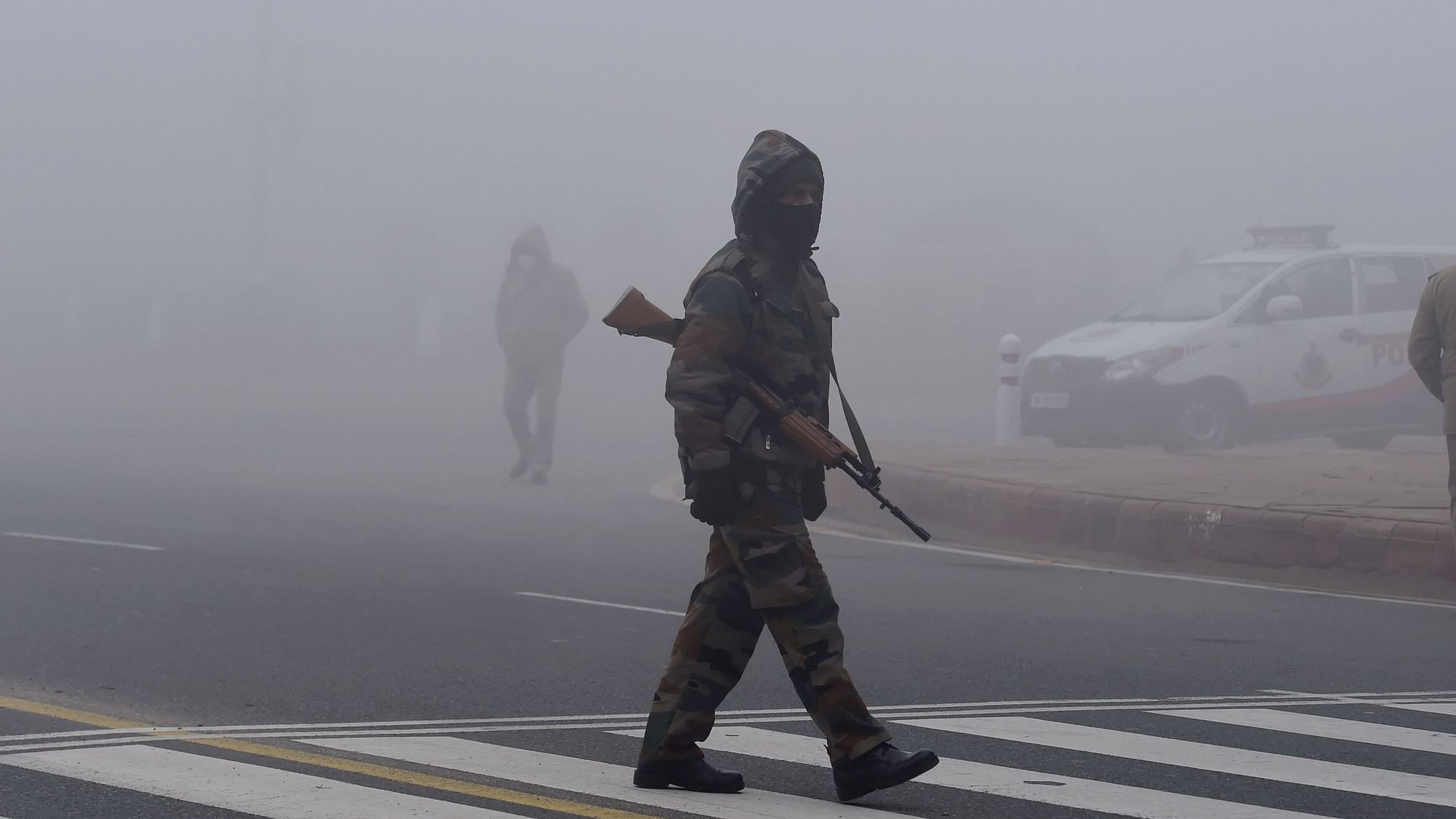 A security personnel walks across a road during the rehearsals for Republic Day Parade amid dense fog at Rajpath, in New Delhi, Saturday, 16 January 2021.&nbsp;