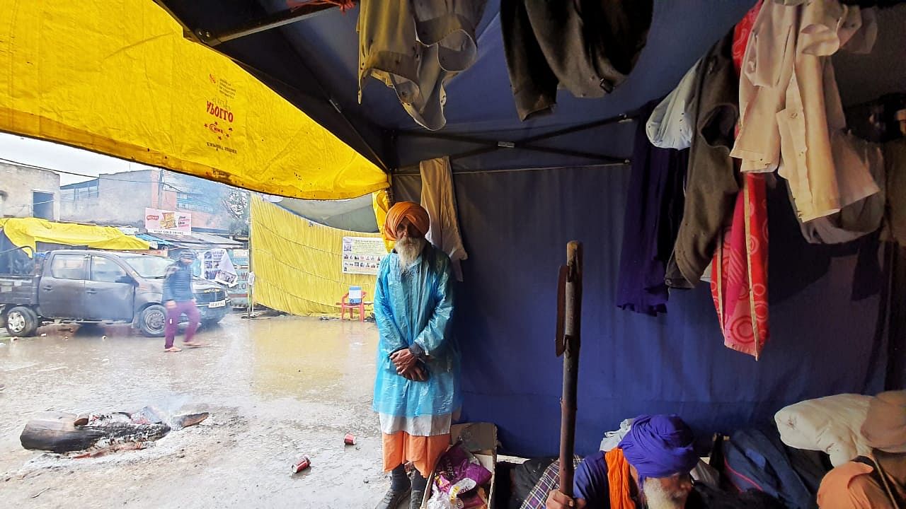A farmer at Singhu Border looks on from inside his tent as rain hits the protest site.