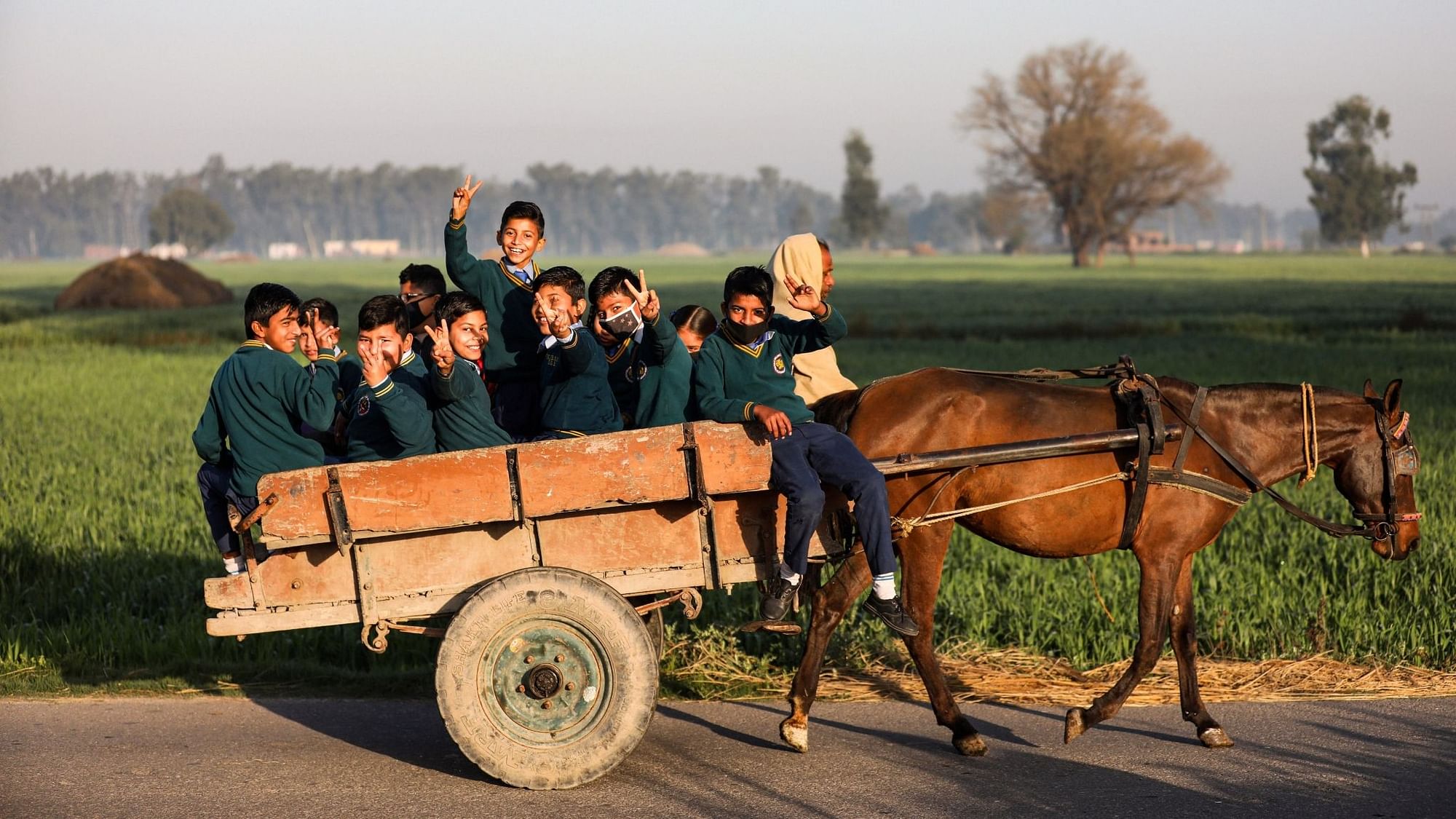 Students travel towards their school on a horse-cart, after schools re-opened since its closure on March 2020 due to the coronavirus pandemic, on the outskirts of Jammu, Wednesday, 3 March, 2021.&nbsp;