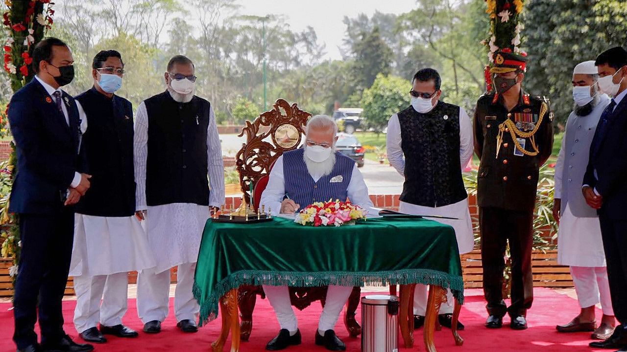Prime Minister Narendra Modi signs the visitor book at the National Martyr’s Memorial in Savar, on the occasion of 50th Independence Day of Bangladesh, in Dhaka, Friday, March 26, 2021