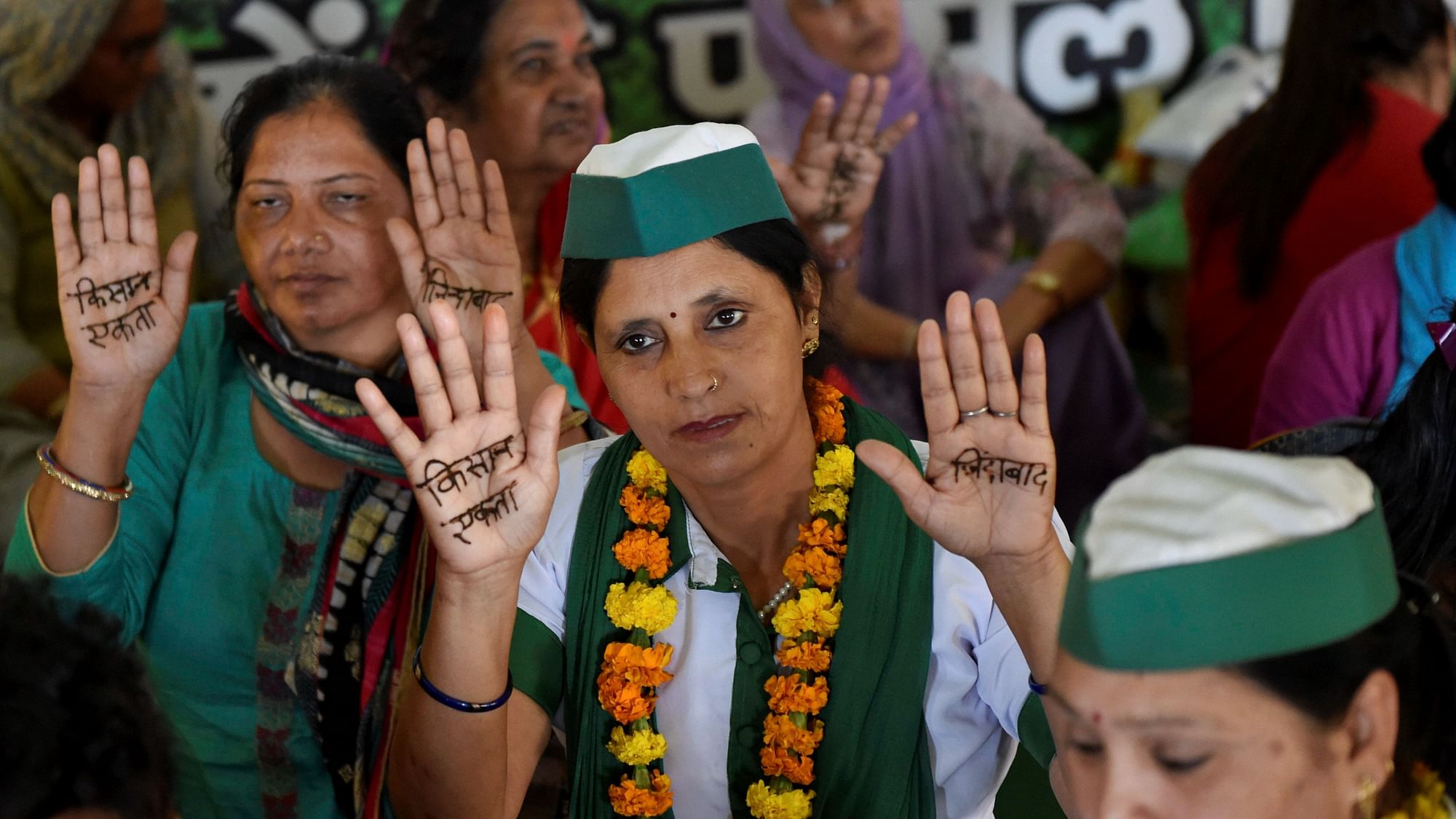 Women show their hands with Kisan Ekta written on them with Henna (Mehandi) to mark International Womens Day, during the farmers’ protest, at Ghazipur Border in New Delhi.