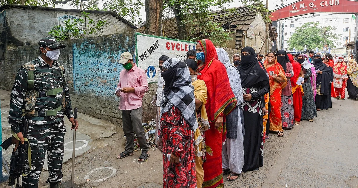 People stand in a queue to cast their vote at a polling station during the 6th phase of State Assembly Election at Birati, in North 24 Parganas. 
