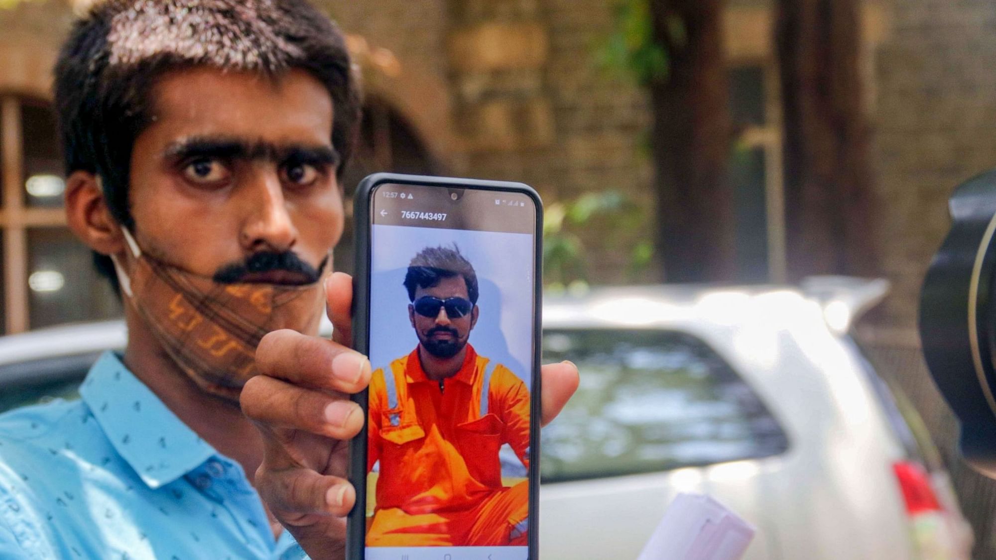 A family member of a&nbsp; victim of cyclone Tauktae, of crew P-305, recovered by the Indian Navy, shows his picture for verification outside the mortuary at JJ Hospital in Mumbai, Friday, 21 May.