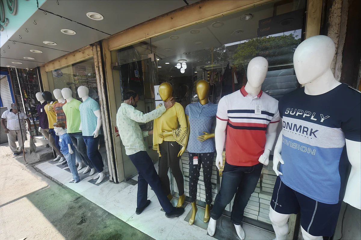 A worker arranges mannequins outside a shop at the Karol Bagh market after further ease in the COVID-19 lockdown, in New Delhi.