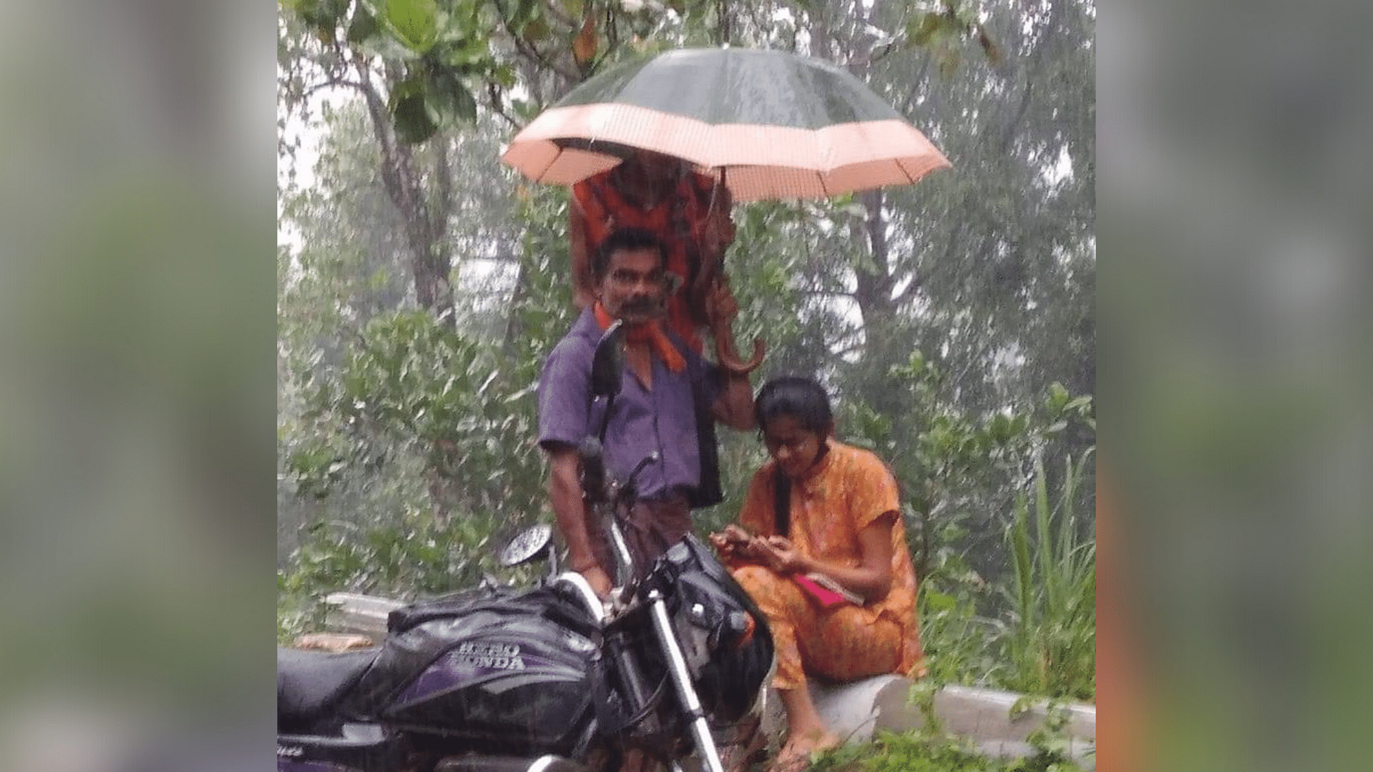Father Holds Umbrella for Daughter Attending Online Classes in the Rain by Roadside