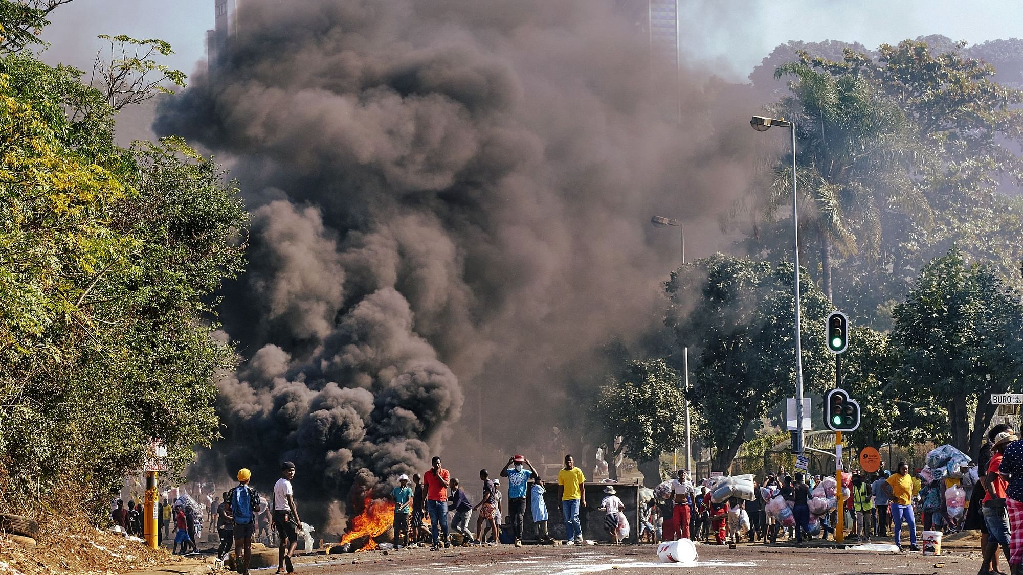 <div class="paragraphs"><p>Looters outside a shopping centre alongside a burning barricade in Durban, South Africa on Monday, 12 July.</p></div>