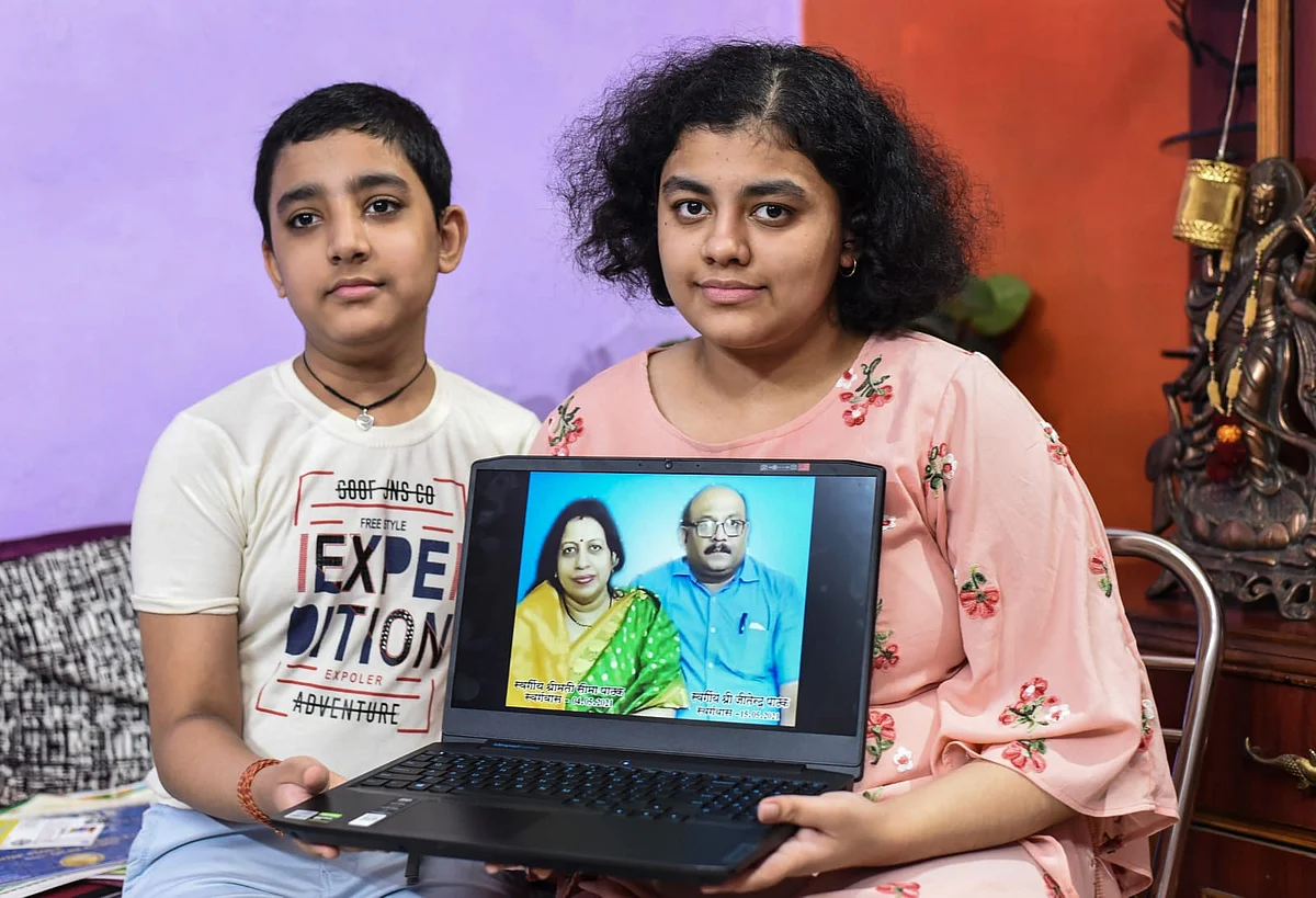 <div class="paragraphs"><p>Vanisha Pathak (R), who emerged as a topper in the class X CBSE exams, along with her brother shows a photograph of her parents on a laptop, at her residence in Bhopal on Thursday, 5 August. Pathak lost both her parents to COVID-19, a few months ago.</p></div>