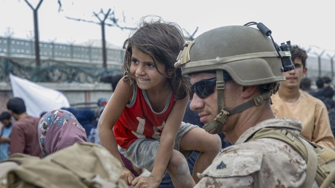 <div class="paragraphs"><p>Kabul: In this image provided by the US Marines, a soldier waits with a child during an evacuation at Hamid Karzai International Airport in Kabul, Afghanistan.</p></div>