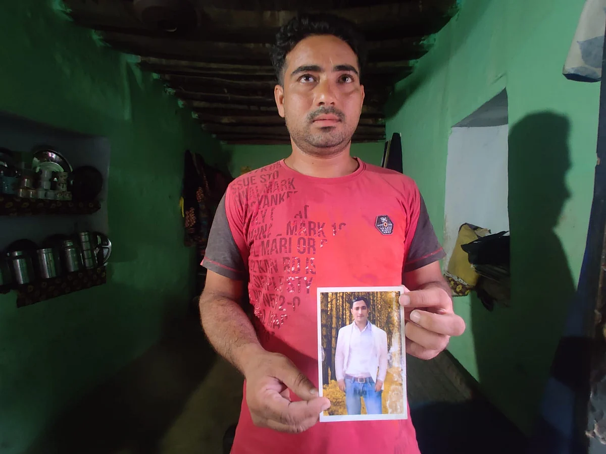 <div class="paragraphs"><p>Shahnawaz's brother, Shehzad, holding his brother's photo at their home in Kawaal village.</p></div>