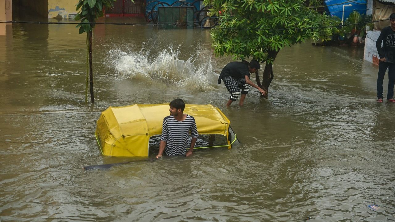 <div class="paragraphs"><p>Lucknow: A man stands near a partially submerged auto rickshaw due to waterlogging following heavy rains.</p></div>
