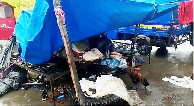 <div class="paragraphs"><p>Resident of Surat's Mafat Nagar Slum taking shelter under platic shed in the rain.</p></div>