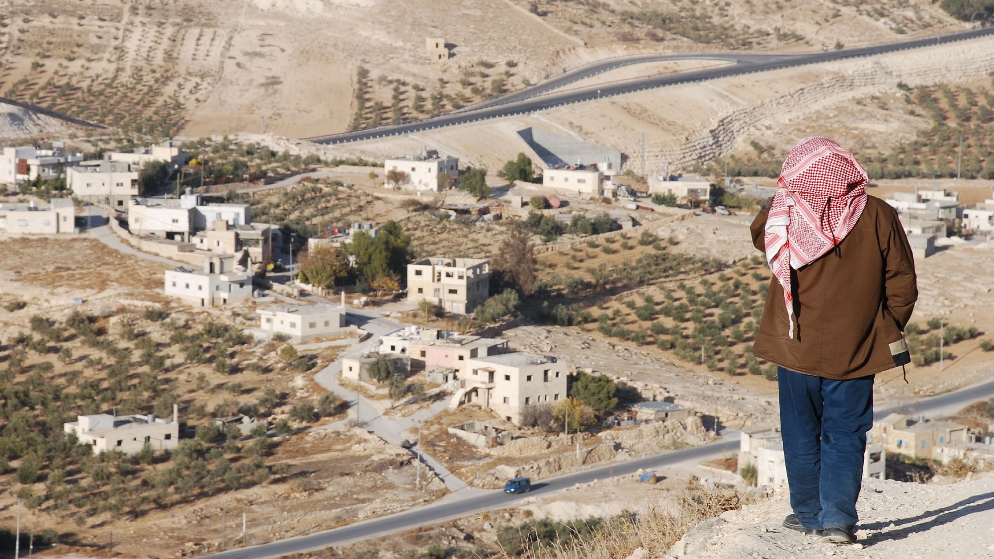 <div class="paragraphs"><p>A Palestinian looks at a village on the outskirts of a town in the West Bank.&nbsp;</p></div>