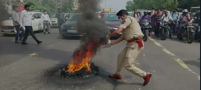 <div class="paragraphs"><p>A policeman putting out the flames on a burning tyre at the Eastern Express Highway in Maharashtra.</p></div>