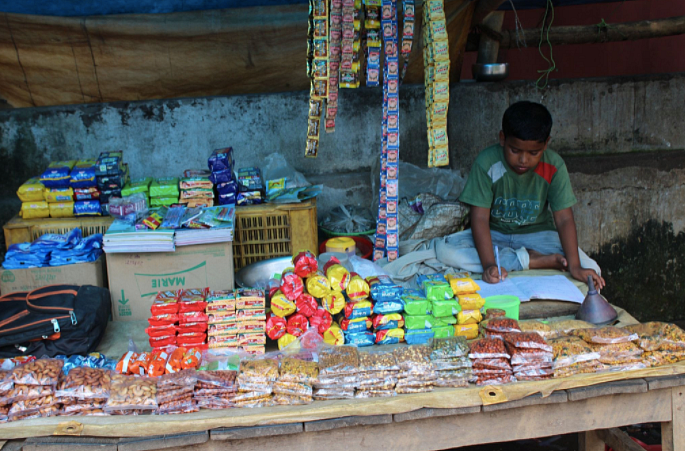 <div class="paragraphs"><p><em>Bikash Giri studying while running his grandfather’s shop.</em></p></div>