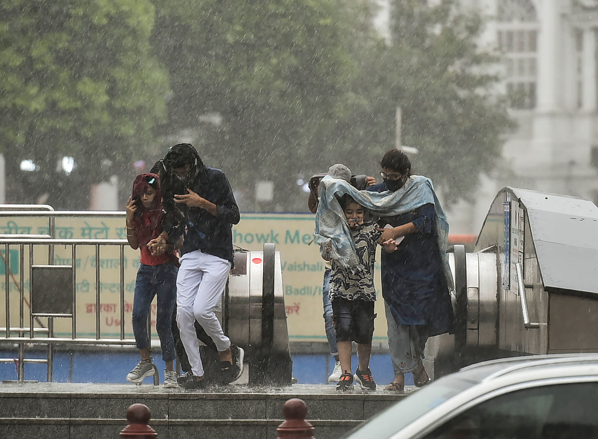 <div class="paragraphs"><p>Pedestrians protect themselves from rain at Connaught Place in New Delhi on Sunday, 17 October.</p></div>