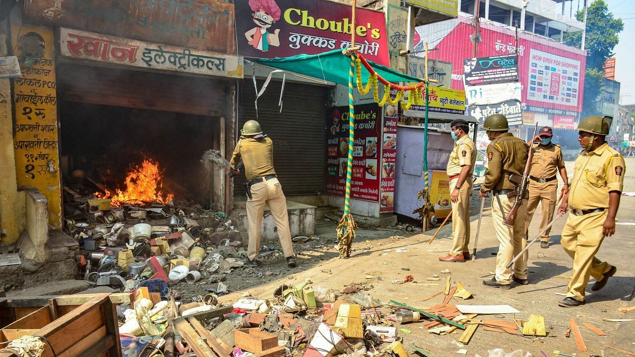 <div class="paragraphs"><p>Amravati: Policemen try to douse a fire in a shop, after a mob went on a rampage during a bandh allegedly organised by BJP, in Amravati, Saturday.</p></div>