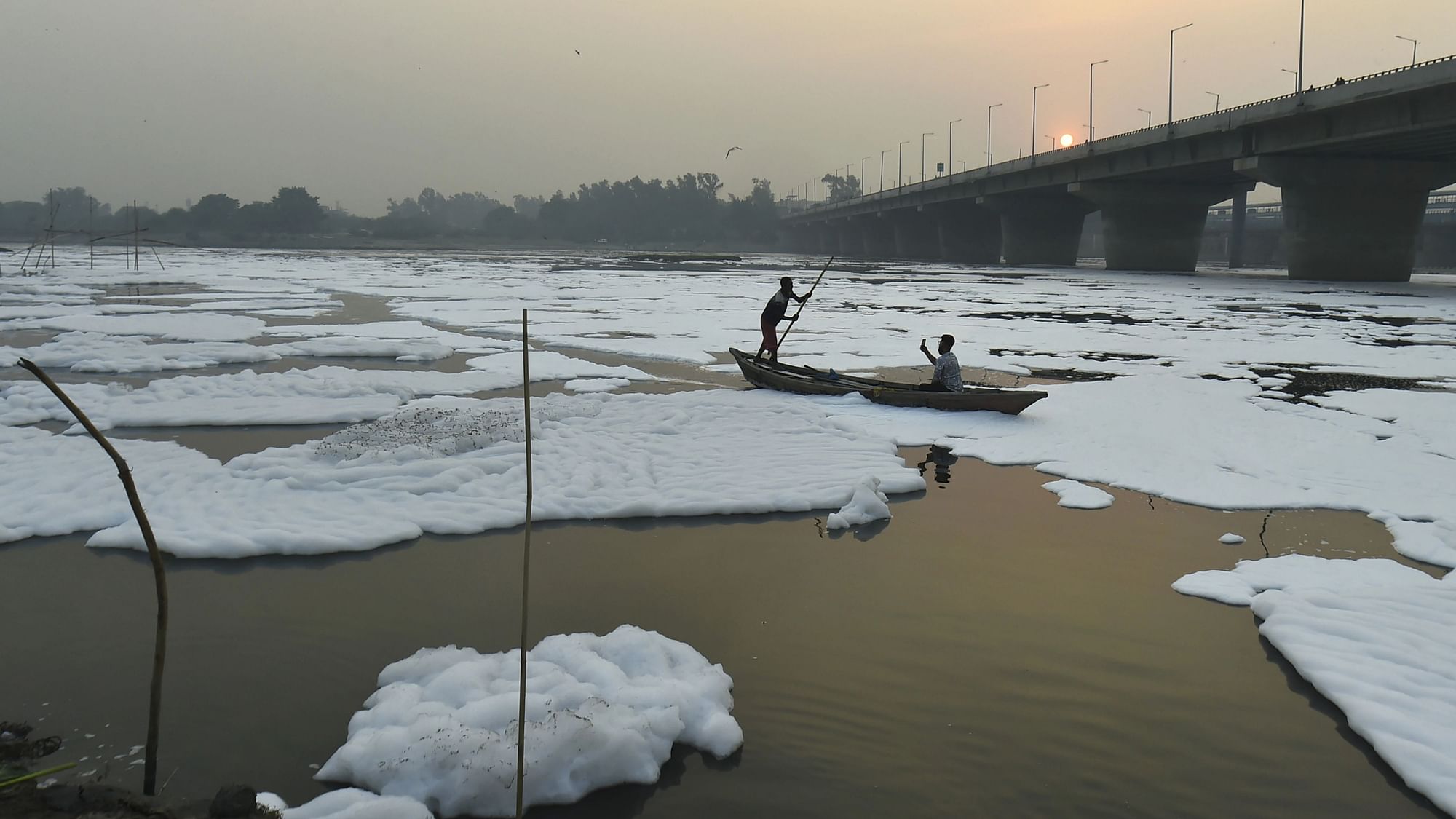 <div class="paragraphs"><p>New Delhi: A boatman moves through a froth-laden polluted Yamuna river, as smog engulfs the sky during sunset, at Kalindi Kunj in New Delhi.</p></div>