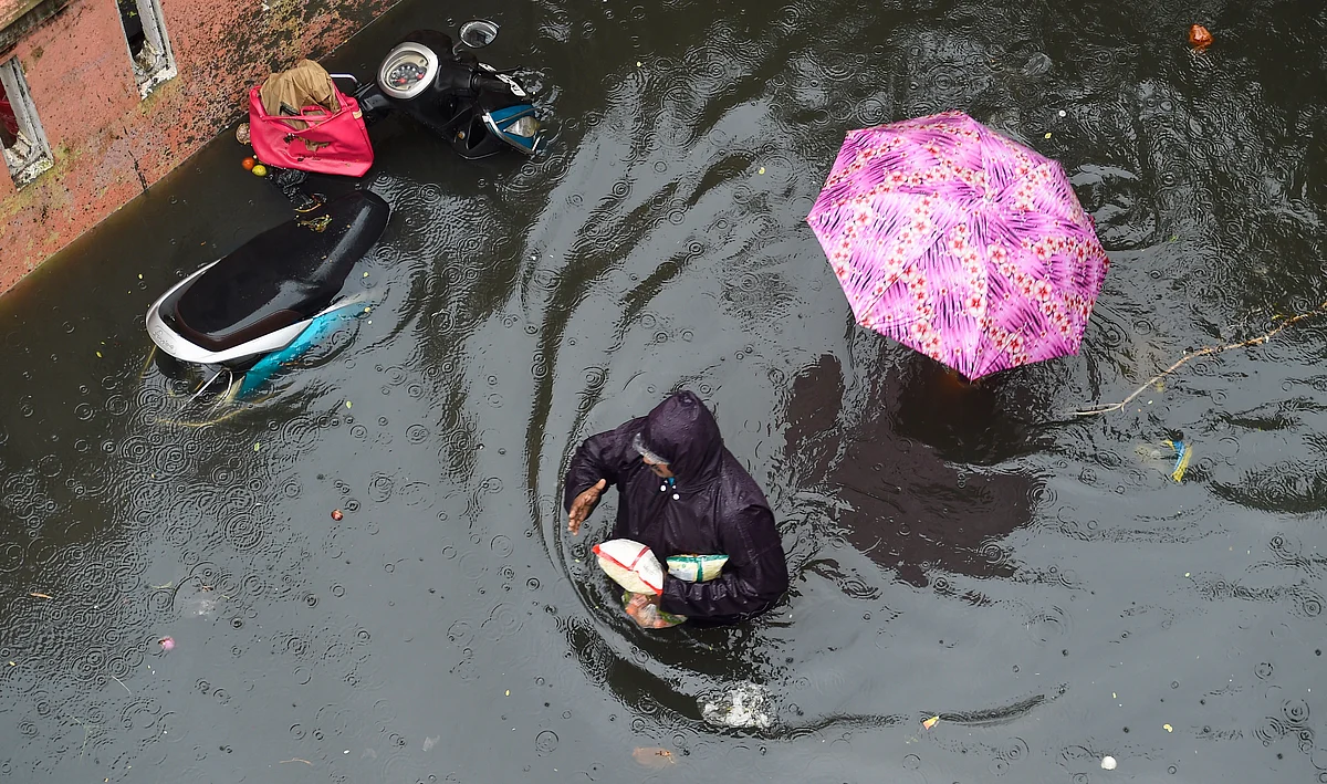 <div class="paragraphs"><p>People wade through a waterlogged street following heavy rain at KM Garden in Purasaiwakkam, in Chennai.</p></div>