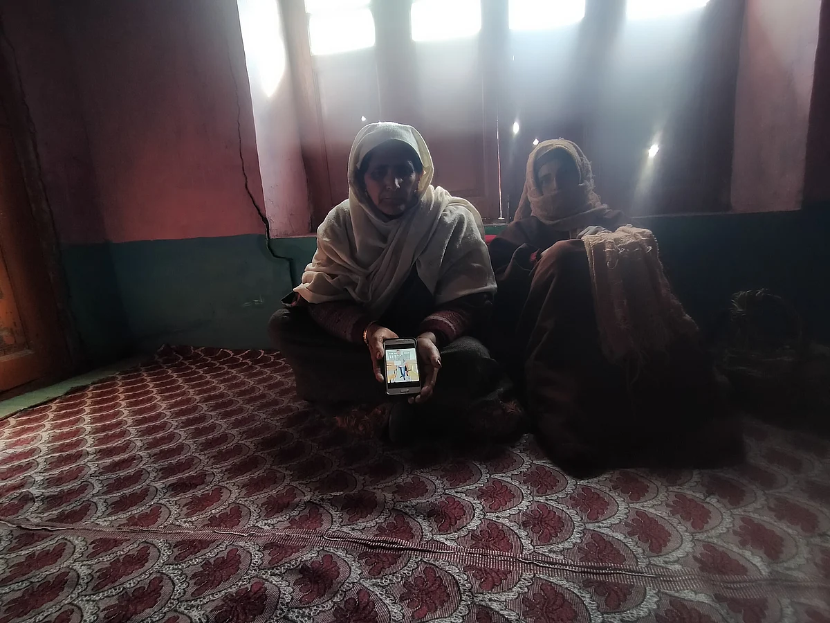 <div class="paragraphs"><p>Hafeeza, Showkat's mother, holding mobile phone displaying his pic.</p></div>