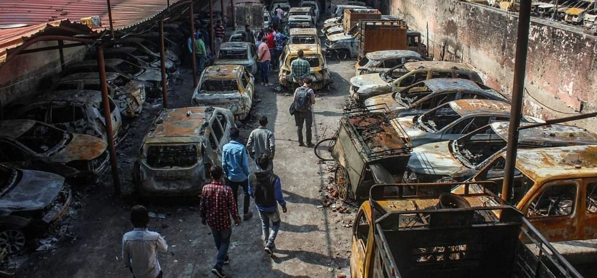 <div class="paragraphs"><p>A group of people looking at the remains of the torched-up vehicles at a parking lot in New Delhi's Mustafabad.</p></div>
