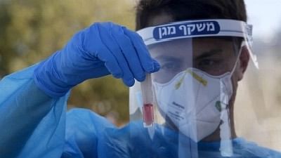 <div class="paragraphs"><p>An Israeli medical worker shows a collected sample for COVID-19 test at a drive-thru testing site. Image used for representational purposes only.</p></div>