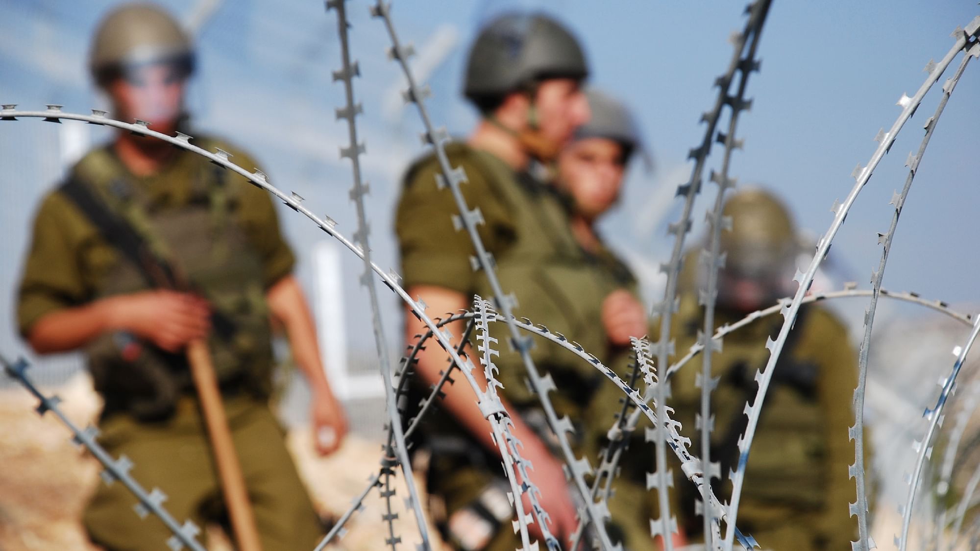 <div class="paragraphs"><p>Four Israeli soldiers stand behind razor wire near a Palestinian village in the West Bank. Image used for representational purposes only.&nbsp;</p></div>