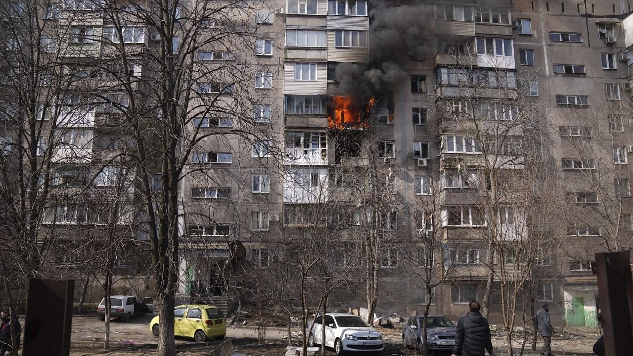 <div class="paragraphs"><p>People look at a burning apartment building in a yard after shelling in Mariupol, Ukraine.&nbsp;</p></div>