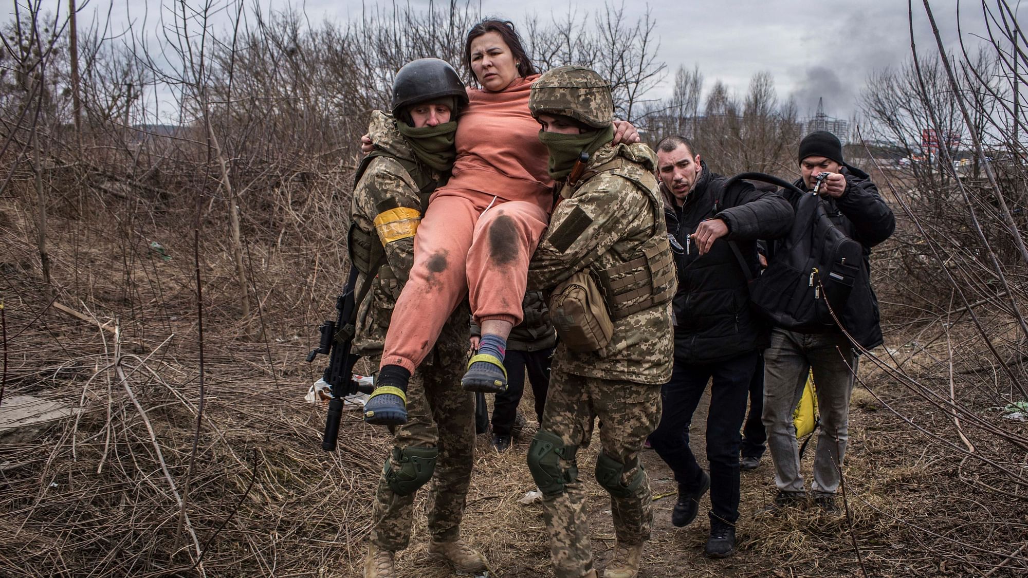 <div class="paragraphs"><p>A woman carried by Ukrainian soldiers crosses an improvised path while fleeing the town of Irpin, Ukraine, Sunday, 6 March.</p></div>