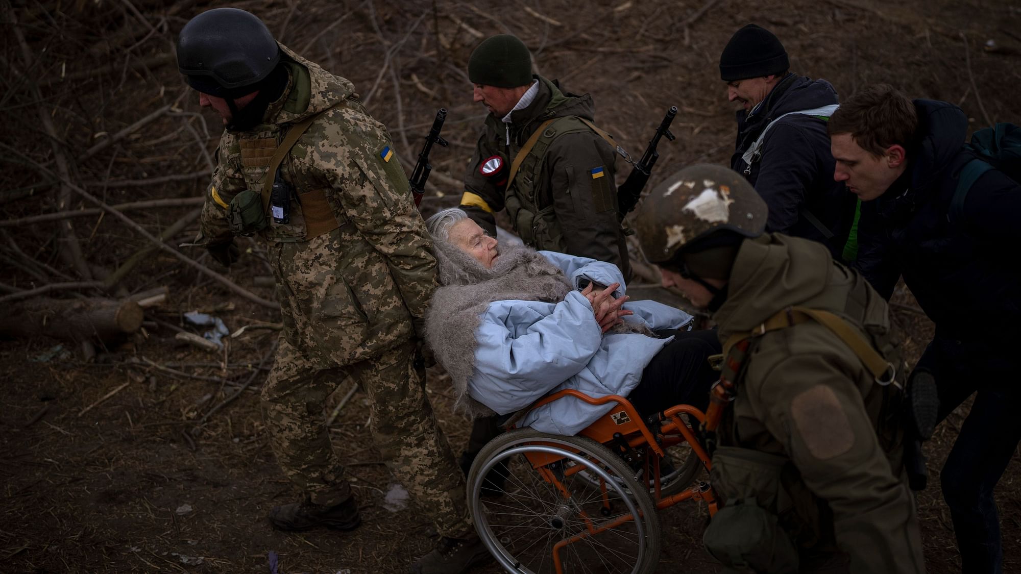<div class="paragraphs"><p>Ukrainian soldiers and militiamen carry a woman in a wheelchair as the artillery echoes nearby, while people flee Irpin on the outskirts of Kyiv, Ukraine, on Monday, 7 March.</p></div>